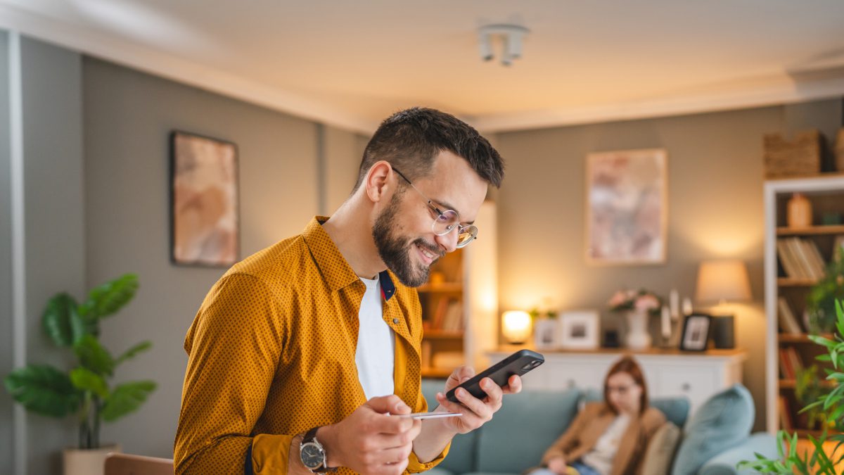 A man in an orange shirt is looking at his phone.