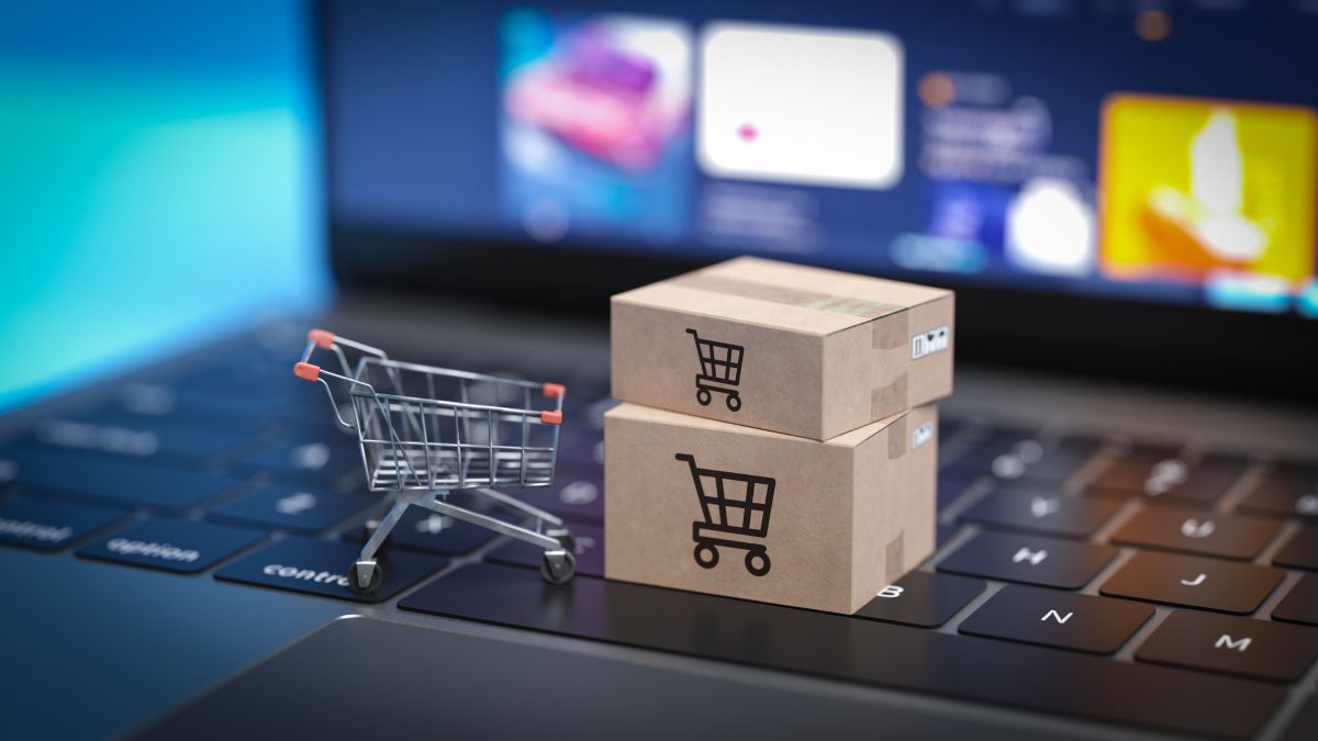 A laptop with two boxes and a shopping cart on top of it.