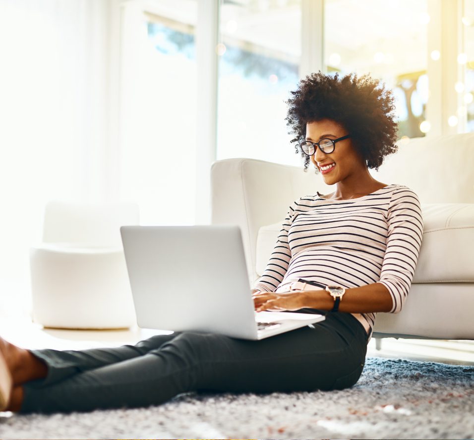 A woman sitting on the floor using her laptop.