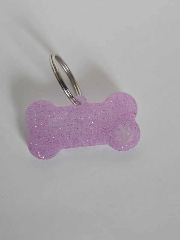 A purple dog bone shaped keychain with a white heart on it.