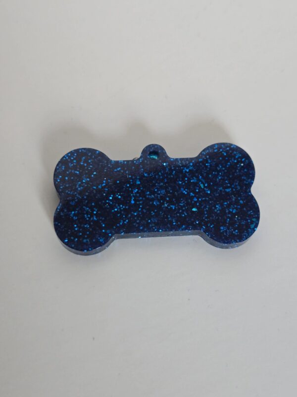 A blue dog bone shaped ornament with black speckles.