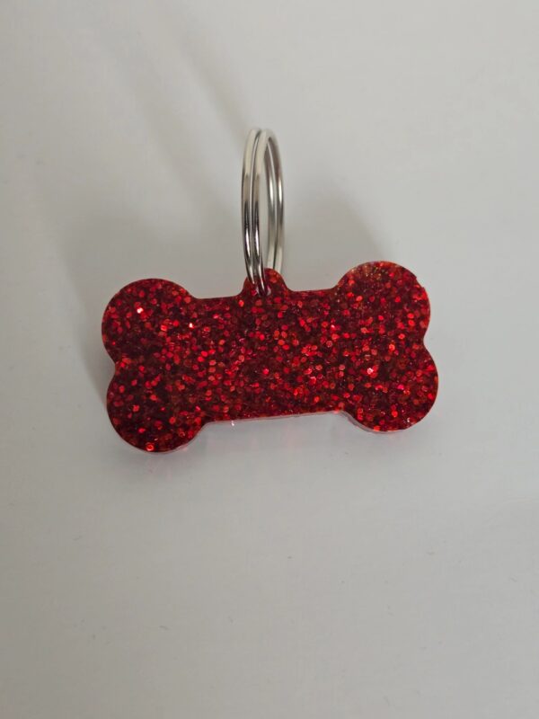 A red dog bone shaped key chain with a white background