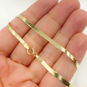 A hand holding a gold chain in front of the camera.