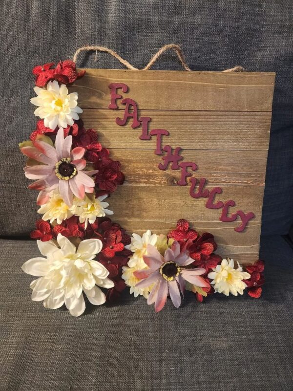 A wooden sign with flowers on it