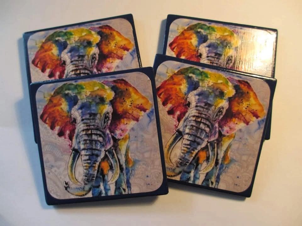 A set of four coasters with an elephant painting on them.