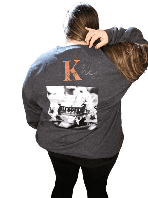 A person wearing a sweatshirt with the letter k on it.
