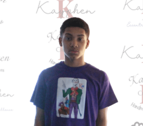 A young man wearing a purple shirt with the joker on it.