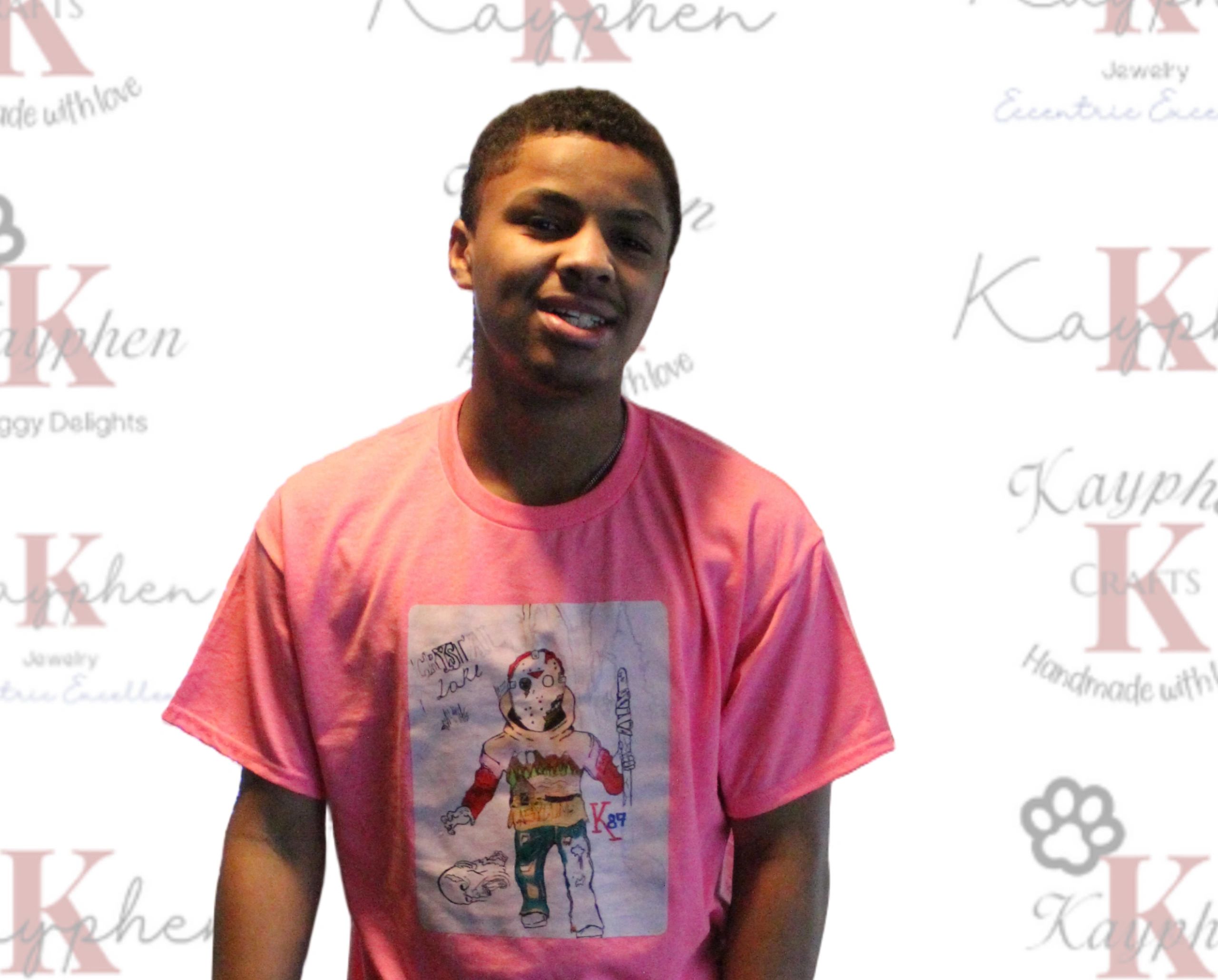 A man in a pink shirt standing next to a wall.