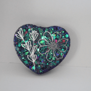 A heart shaped pin with flowers on it.