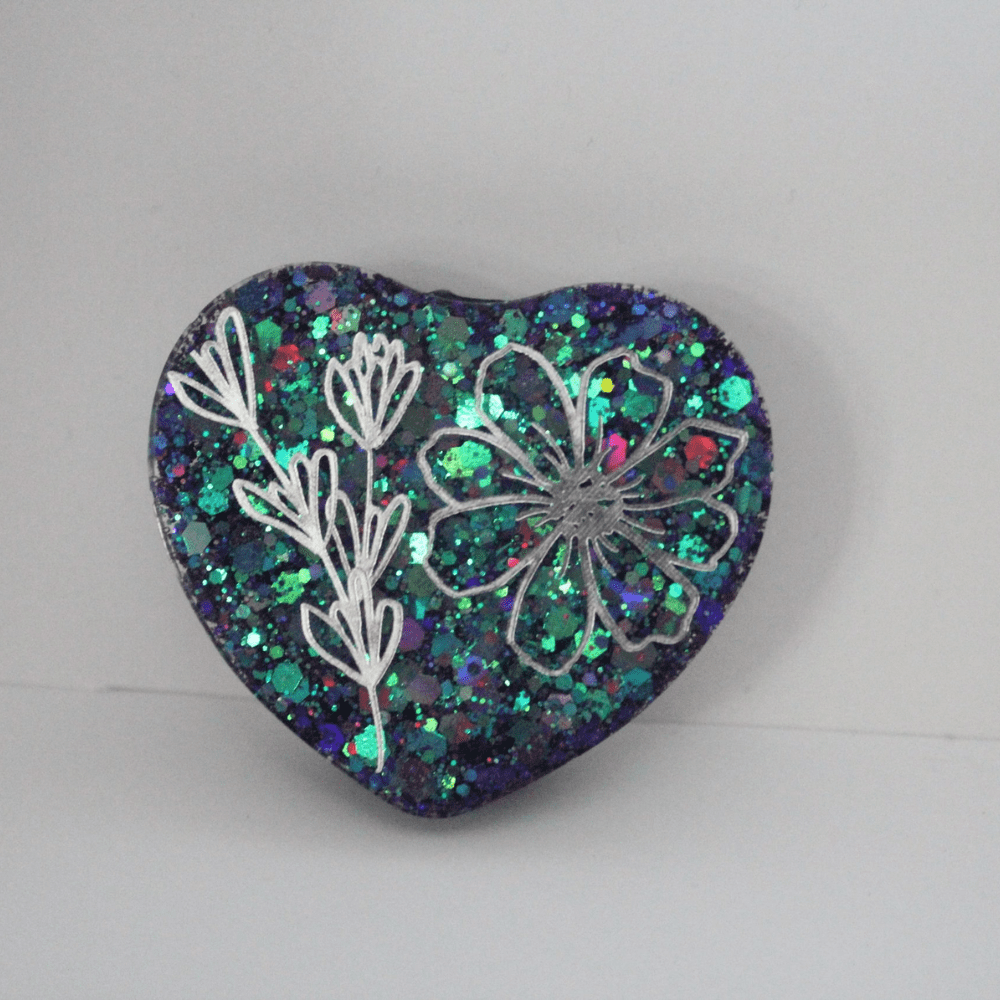 A heart shaped pin with flowers on it.