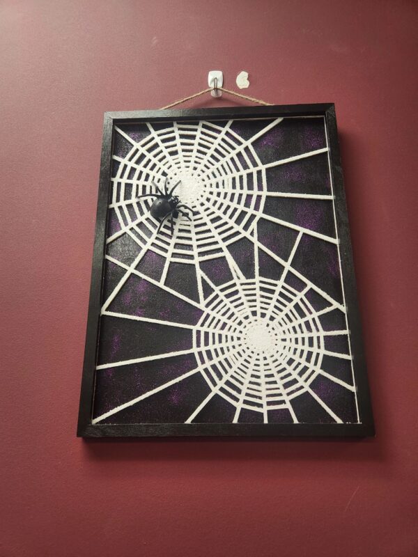 A spider web picture hanging on the wall.