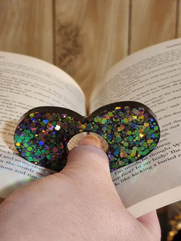 A person is holding onto a book with a pair of glasses on it.