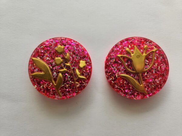Two pink and red round shaped cookies with gold leaf.