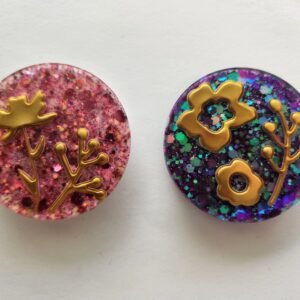 Two round shaped buttons with different designs on them.