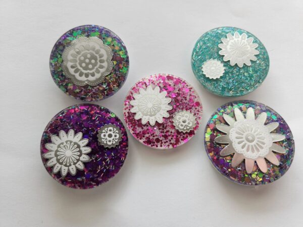 A group of five buttons with different designs on them.