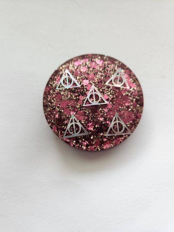 A button with pink and silver glitter on it.
