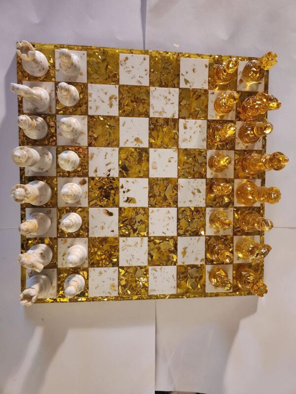 A gold and white chess board with pieces on it.