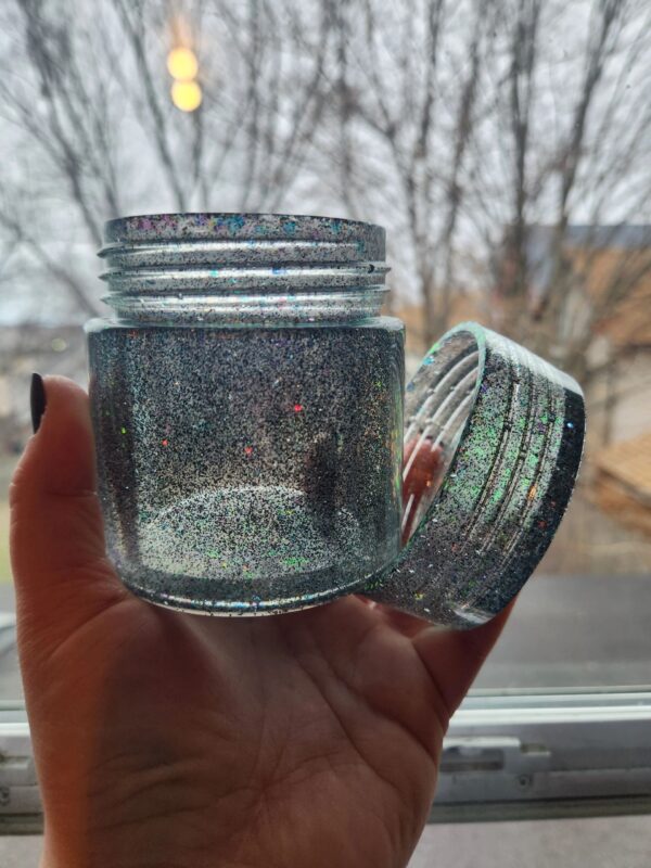 A person holding a jar with a lid open.
