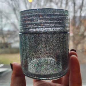 A person holding onto a jar of glitter