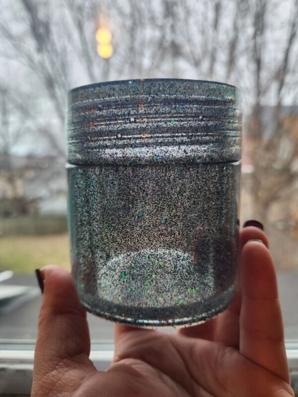 A person holding onto a jar of glitter