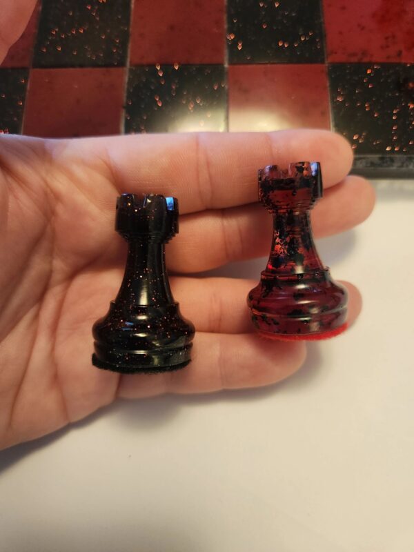 A person holding two chess pieces in their hand.