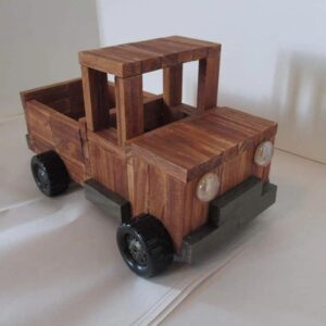 A wooden toy truck is sitting on the floor.