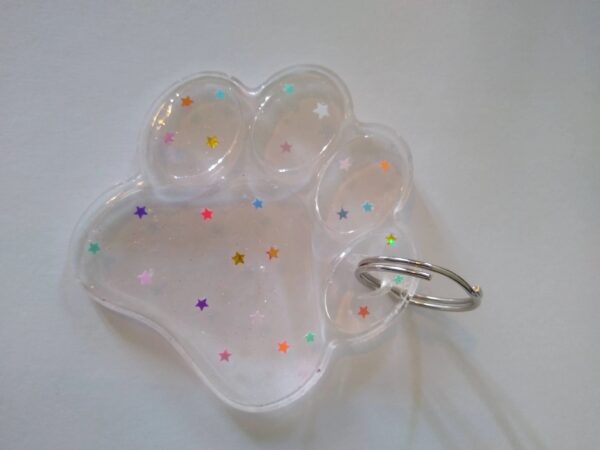 A white paw shaped keychain with colorful dots.