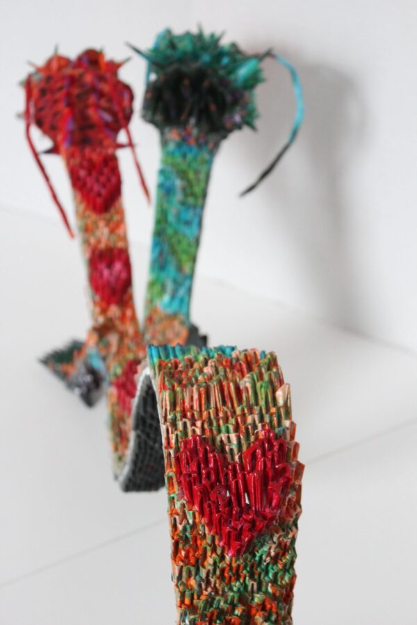 A close up of three different colored yarn sculptures