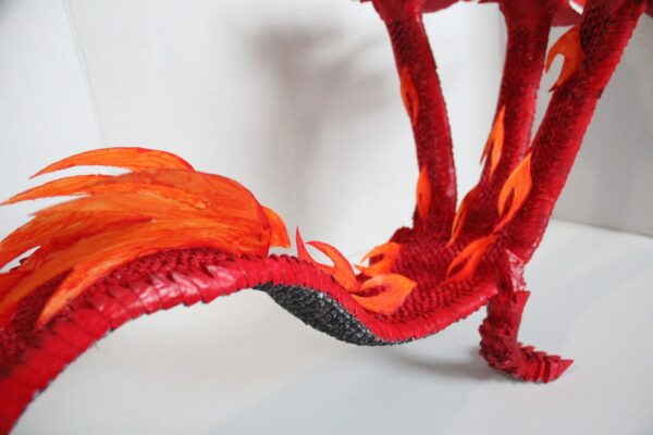 A red dragon with orange flames and black feet.