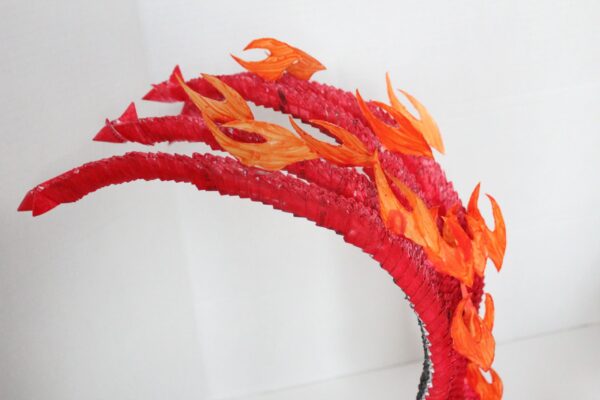 A red and orange fire sculpture on top of a white wall.