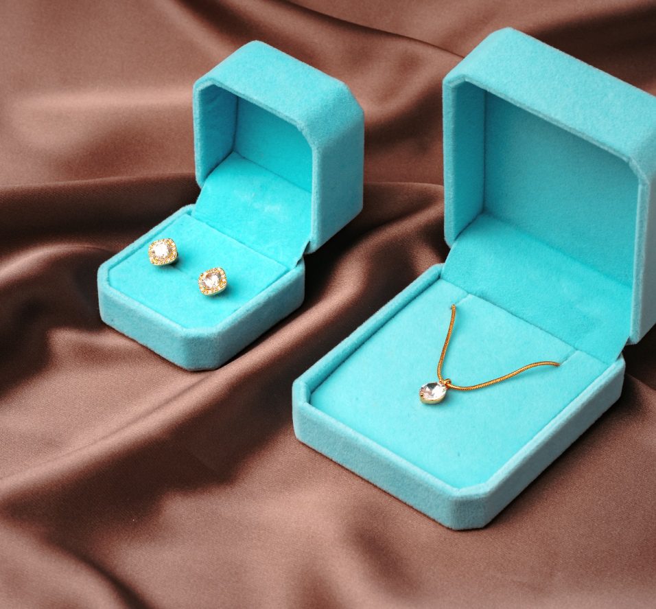 A pair of earrings and necklace in blue boxes.