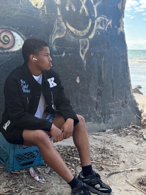 Person sitting by graffiti wall at beach.