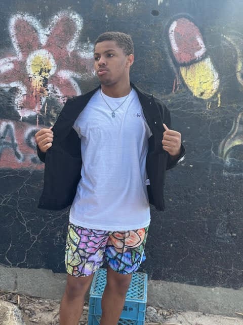 Man posing in front of graffiti wall.