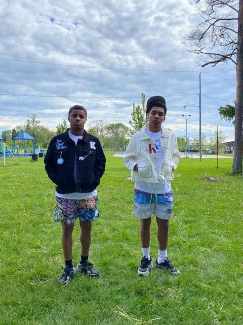 Two boys standing on grassy field.