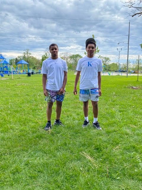 Two people standing on green grass.