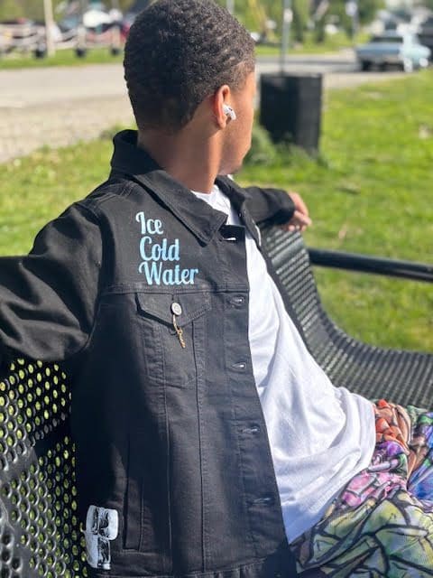 Person sitting on bench wearing black jacket.