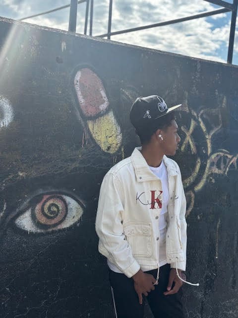 Person standing by graffiti-covered wall, outdoors.