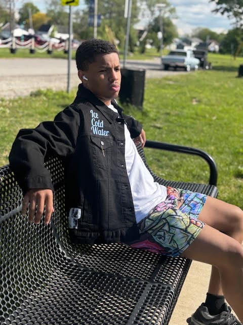 Teen sitting on a park bench, thinking.
