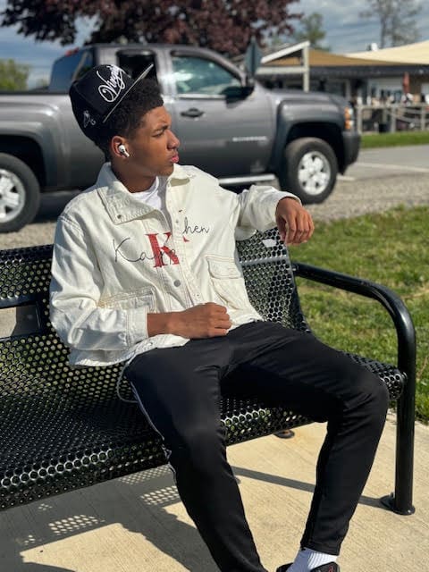Person sitting on bench, wearing cap outdoors.