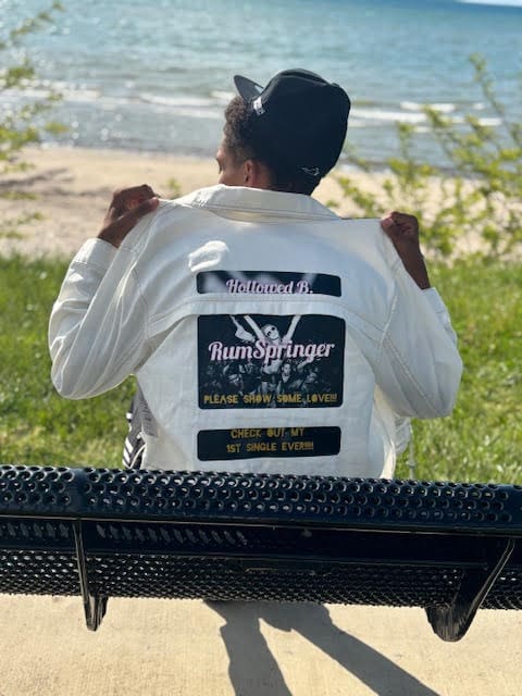 Person on bench wearing custom jacket by water.