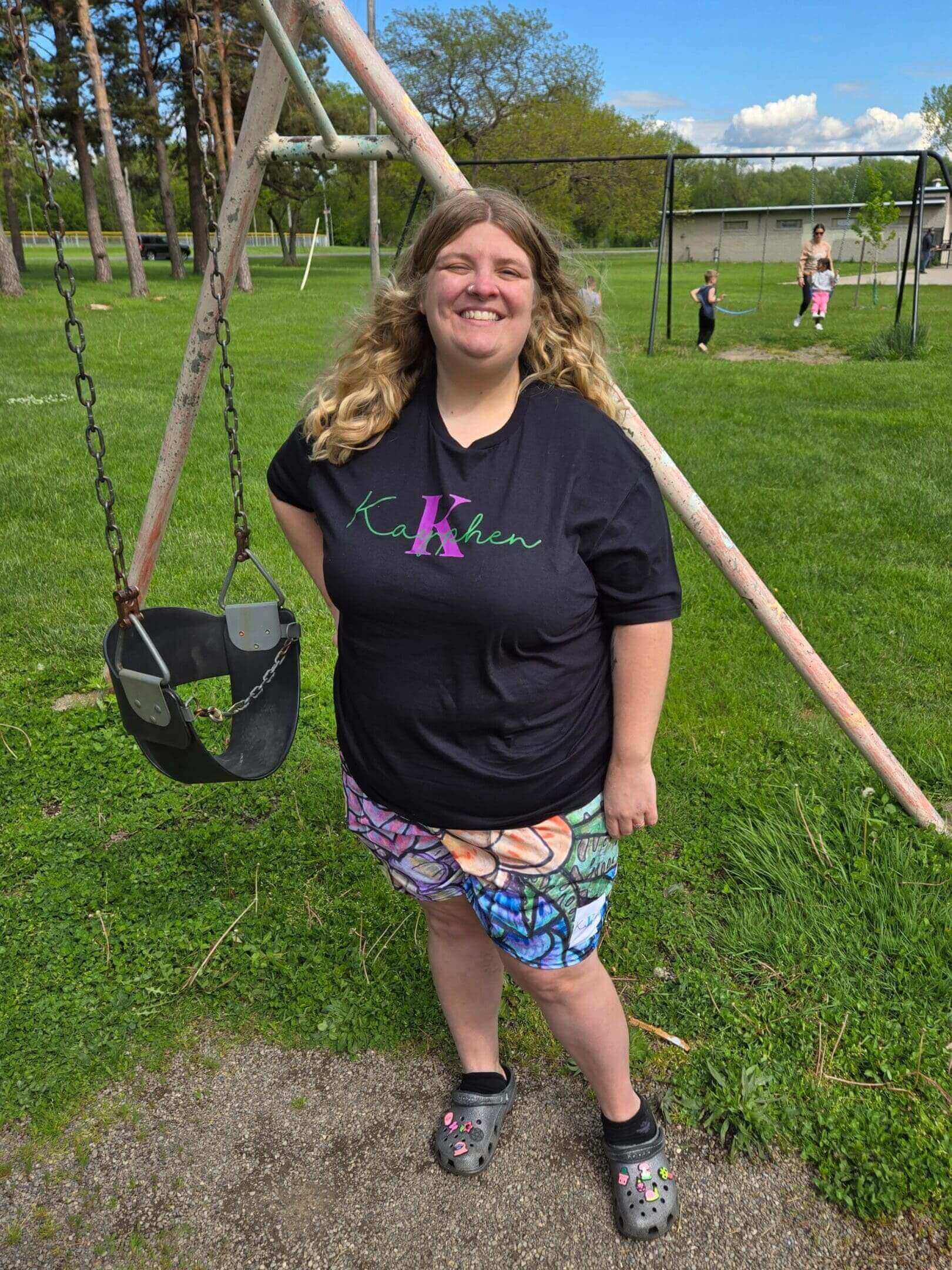Woman smiling near playground swing set.