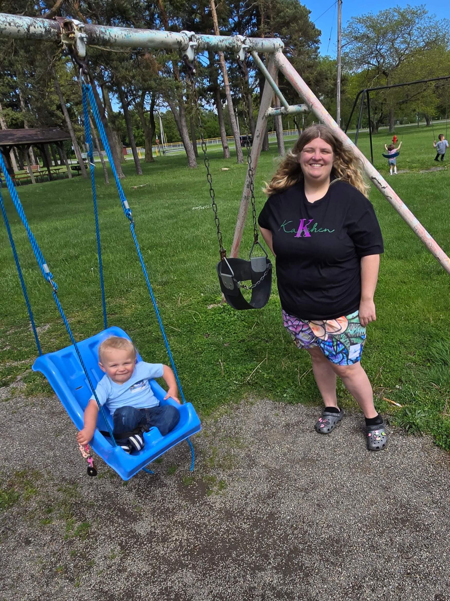 Woman and child at park swing set.