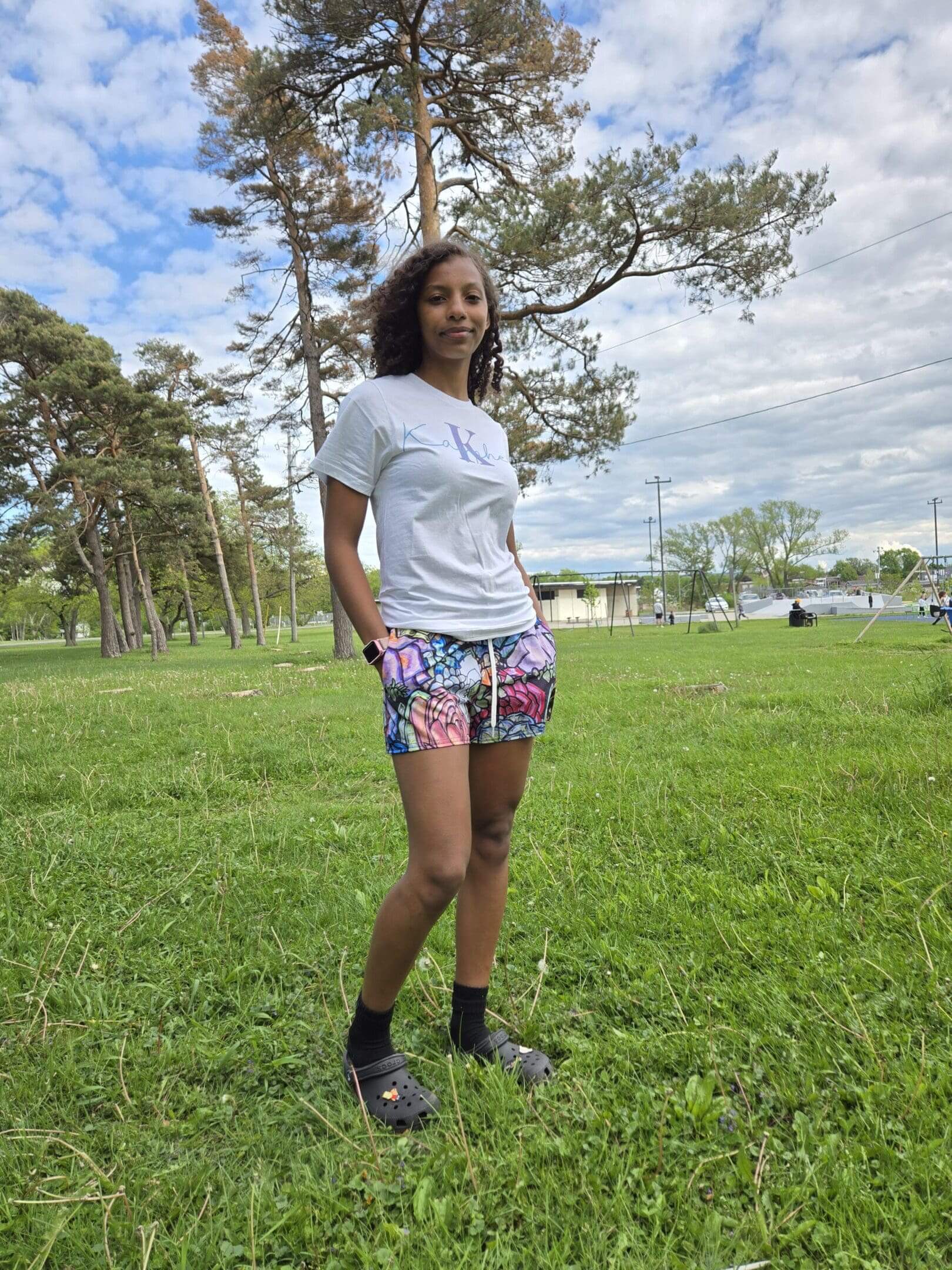 Woman standing on grass in park setting.