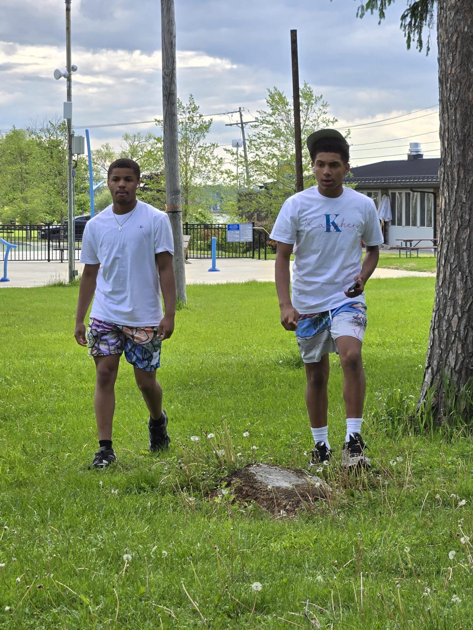 Two people walking in a grassy park.
